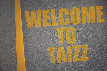 asphalt road with text welcome to Taizz near yellow line.