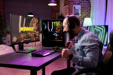 Gamer ecstatic after killing other players in online multiplayer shooting game and winning tournament. Man at computer desk releasing pent up emotions, doing victorious yelling after defeating foes