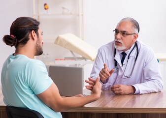 Fototapeta premium Injured young man visiting old doctor