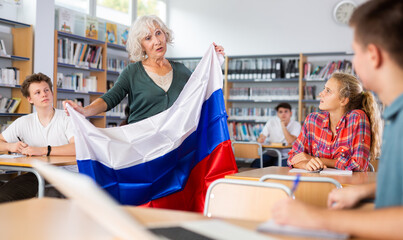 Interesting story about Russia while teaching high school students in school library. Teacher holds the flag of Russia in her hands