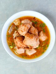 bakso, meatballs served in a bowl on a gray background. Meatball soup with marrow, chicken bones and spring onions without noodles or vermicelli. savory and delicious soupy food. Vertical shot