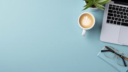 A tidy workspace with a laptop, coffee cup, and plant on a blue background - obrazy, fototapety, plakaty