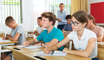 Fototapeta premium Pupils sitting in class and listening carefully to male teacher.