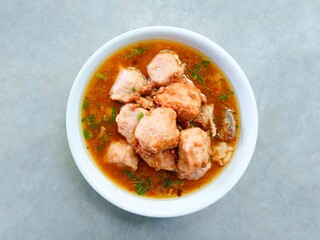 bakso, meatballs served in a bowl on a gray background. Meatball soup with marrow, chicken bones and spring onions without noodles or vermicelli. savory and delicious soupy food.