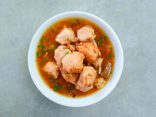 Top view of bakso, meatballs served in a bowl on a gray background. Meatball soup with marrow, chicken bones and spring onions without noodles or vermicelli. savory and delicious soupy food.