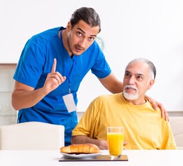 Young male doctor visiting old patient at home
