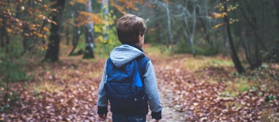 Young boy walking on a path in the forest from behind