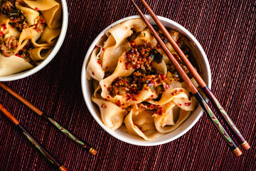 Bowls of Biang Biang Noodles Topped with Spicy Chili Oil Sauce: Biang biang mian topped with minced...