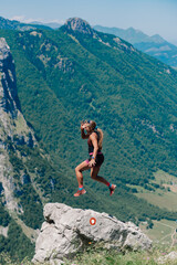 Naklejka na ściany i meble A skyrunner is jumping on a and trail running in rocky mountains.