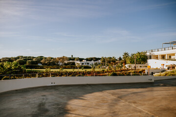 Fototapeta na wymiar Sotogrante, Spain - January 25, 2024 - Outdoor view of a landscaped area with manicured lawns, palm trees, and white buildings in the background under a clear blue sky.