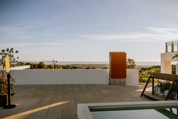 Sotogrante, Spain - January 25, 2024 - Terrace with a view of distant hills, an art piece, plants, and a clear sky at sunset.
