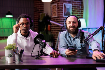 Skillful cohosts presenting entertaining show in professional studio produced for streaming services. Presenter using high quality recording setup to film internet channel vlog