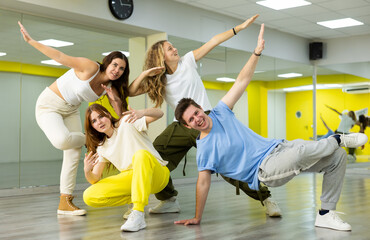 Team of positive teenagers rehearsing modern dances in dance hall