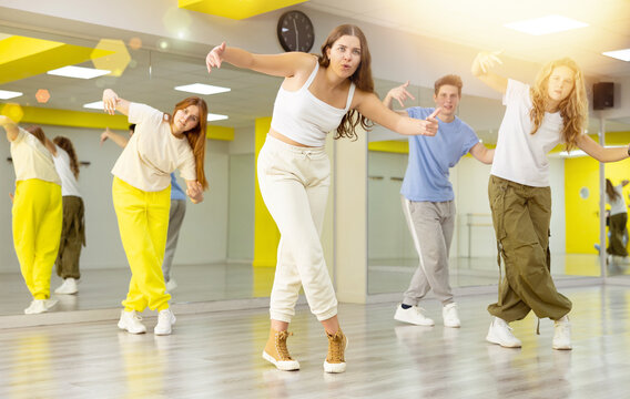 Energetic young girl engaging in breakdance in dance studio. Teenagers training Toprock moves