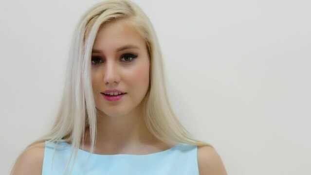 Attractive blonde looks downward and blinks, on white background
