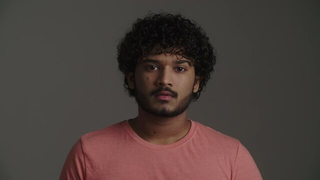 An attractive serious african american guy with a direct, slight sad and pensive gaze expects frankness. A young thoughtful man in downcast emotions demonstrates disappointment, mistrust and