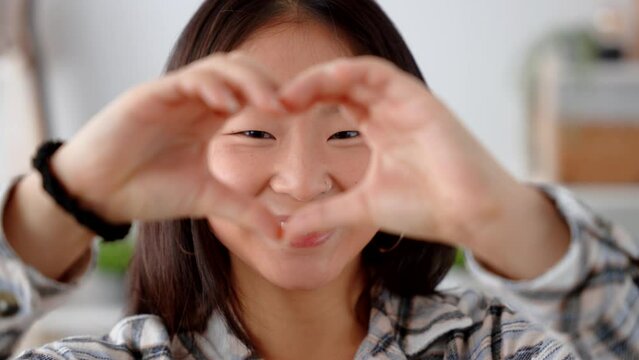 Closeup of Chinese woman showing heart or love shape with hands.
