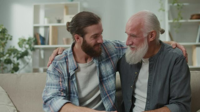 Family conversation on the couch: young and elderly men talk about life, psychological support for each other, cross-generational dialogue, heartfelt consolation, advice and wisdom, warm communication