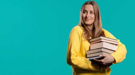 Happy student woman with stack books from library, blue background. Copy space
