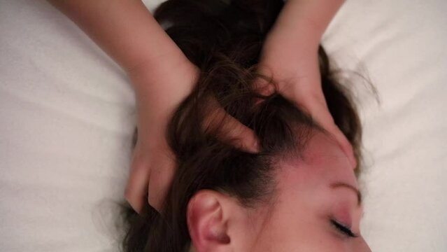 Masseur makes head massage for client in spa center, slow motion