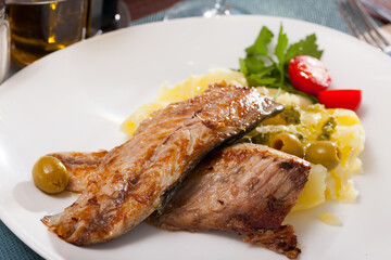Fried mackerel fish with mashed potatoes, parsley and olives served on plate