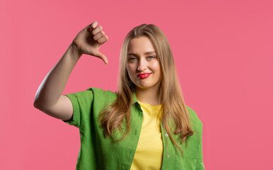 Pretty woman with sign of dislike. Young millennial girl showing thumbs-down