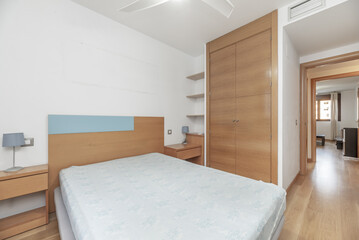 Fototapeta na wymiar A bedroom with light wood furniture and a matching wooden built-in wardrobe