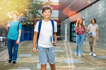Portrait of teenager boy going to school lessons on sunny day with his friends