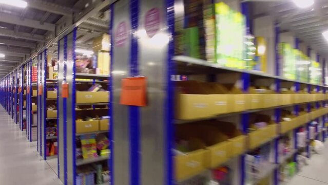 Rows of shelves with products in large warehouse of OZON internet shop