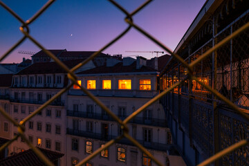 Night view to the downtown cityscape in Lisbon from the grid fence of Santa Justa Elevator in...
