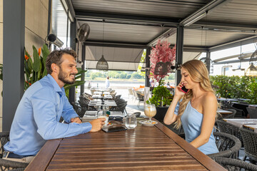 Happy couple talking and drinking coffee at the outdoor cafe