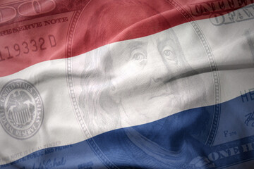 waving colorful flag of netherlands on a american dollar money background. finance concept.