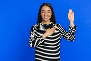 I swear to be honest. Sincere responsible smiling woman raising hand to take oath, promising to be...