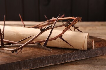 Crown of thorns and old scroll on wooden table, closeup