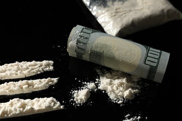 Drug addiction. Cocaine and rolled dollar banknote on black table, closeup - obrazy, fototapety, plakaty