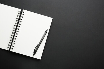 Notebook and pen on black background, top view. Space for text