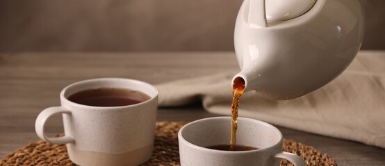 Pouring aromatic tea into cup at table, closeup