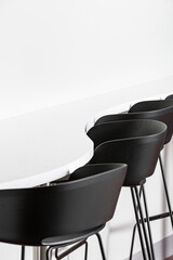 Black stools lined up around a curved white bench.