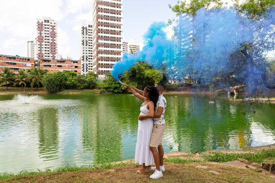 Happy couple having a gender reveal party. blue smoke grenade outdoors. It's a boy. Gender reveal party concept.