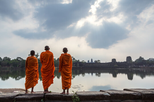 Three buddhist monks in front of Angkor Wat temple and lake, Siem Reap, Cambodia