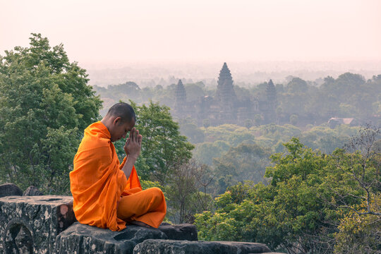 Buddhist monk meditating with Angkor wat temple in the background, Cambodia