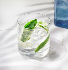 The crisp, clear drink stands beside a striking blue bottle, creating a visually stunning composition that captures the essence of upscale mixology.