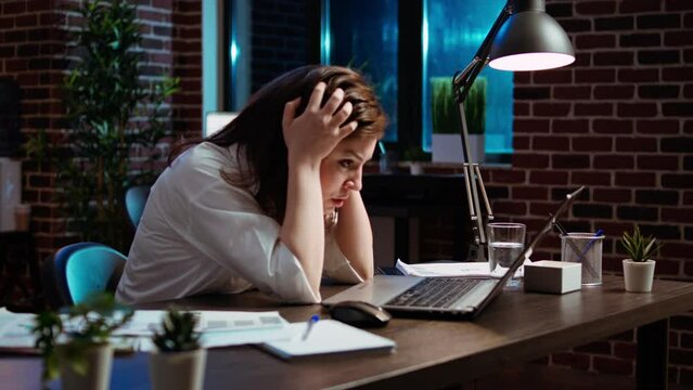 Employee upset by negative response received from customer while discussing business matters over email messages. Worker exasperated, putting head in head, frustrated by too much work in office