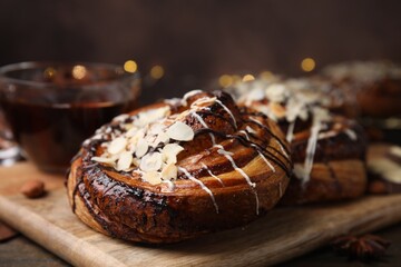 Delicious rolls with toppings and nuts on wooden table, closeup. Sweet buns