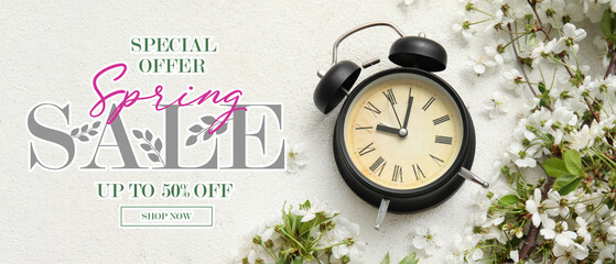 Blooming spring branches and alarm clock on light background. Spring Sale