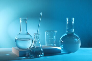 Laboratory analysis. Different glassware on table against light blue background