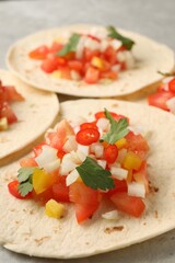 Delicious tacos with vegetables and parsley on grey table, closeup
