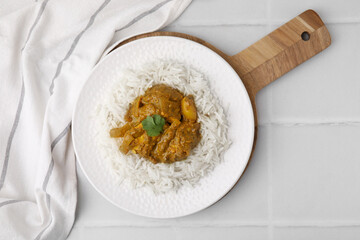 Delicious chicken curry with rice on white tiled table, top view