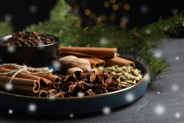 Different spices and fir tree branches on dark table, closeup. Cinnamon, cloves, anise, cardamom,...