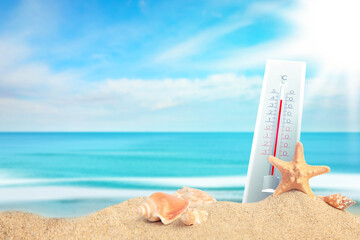 Thermometer on beach showing high temperature during hot day in summer
